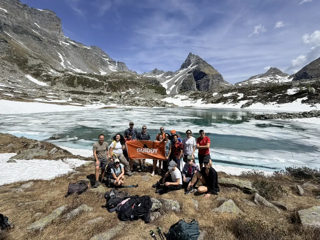 Guidders con la bandiera arancione di Guiddy davanti a un lago ghiacciato d'alta quota