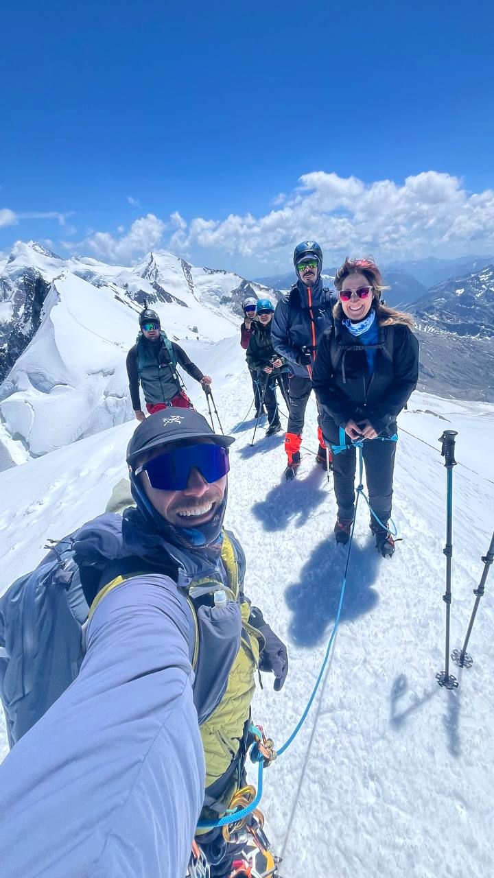Selfie di gruppo in vetta con le Alpi innevate dietro